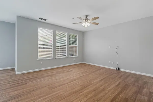 a view of an empty room with wooden floor and window