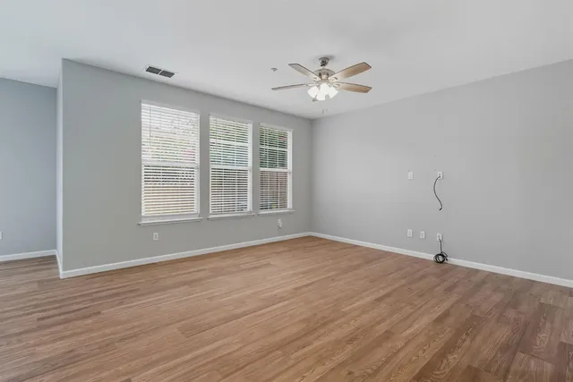 a view of an empty room with wooden floor and window