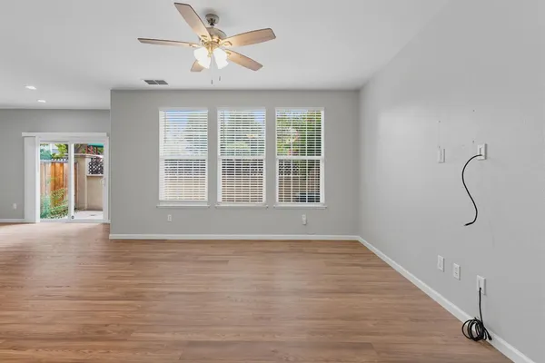 a view of an empty room with window and wooden floor