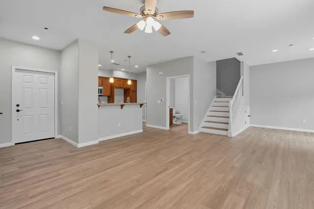 a view of an empty room with wooden floor and a ceiling fan