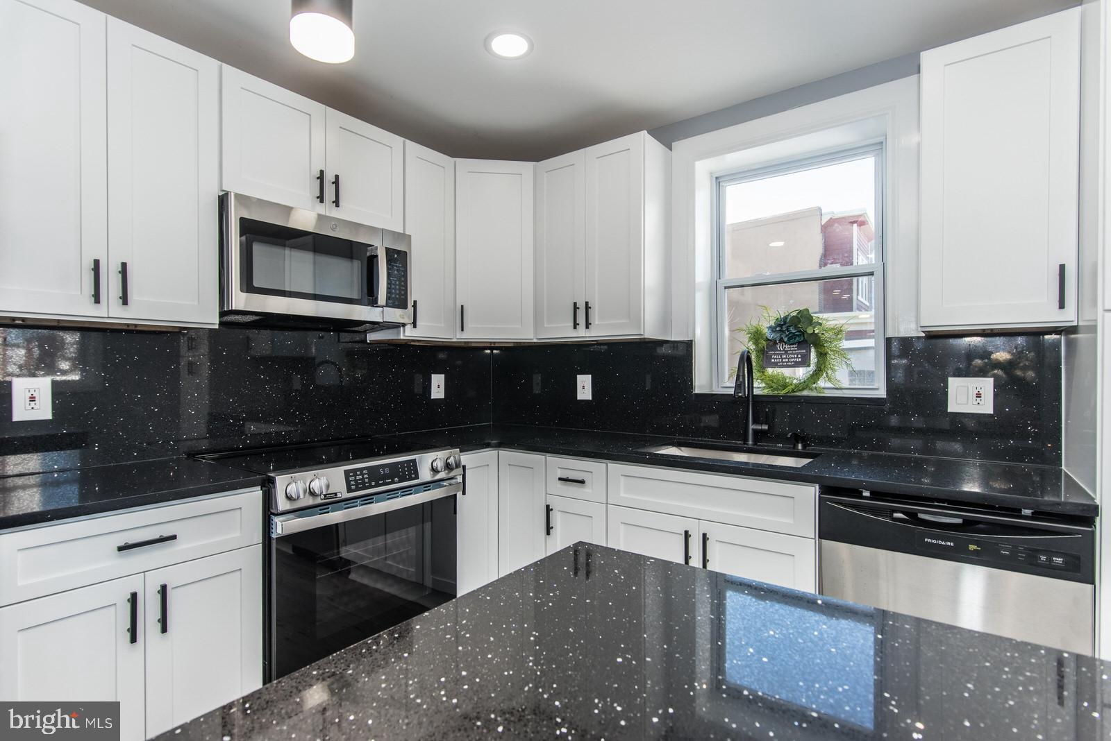 460 Robbins Street Philadelphia, PA 19111 - Photo 9 of 34 a kitchen with granite countertop wooden cabinets and a stove top oven