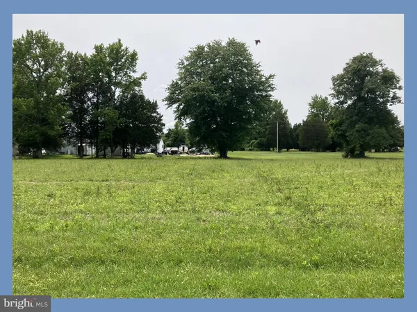 a view of a green field with trees in the background