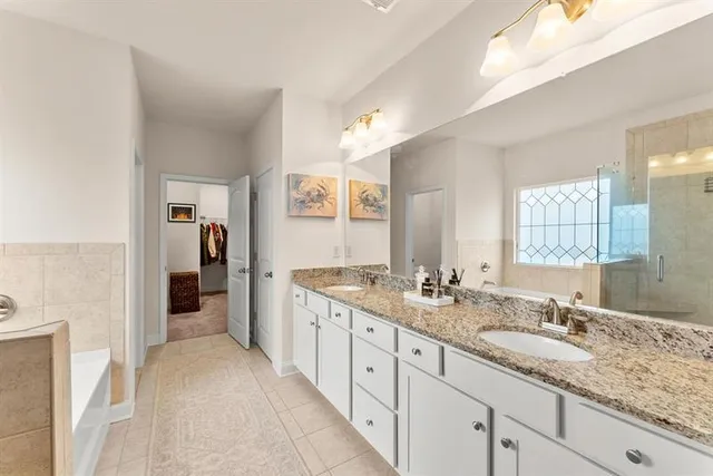 a spacious bathroom with a granite countertop double vanity sink a mirror and a