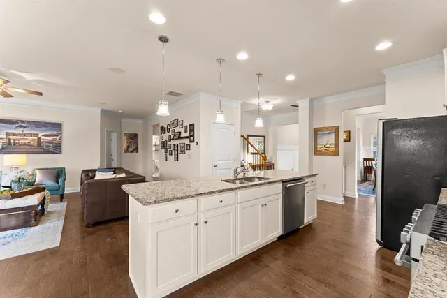 a kitchen with stainless steel appliances kitchen island granite countertop a refrigerator a sink dishwasher a dining table and chairs with wooden floor