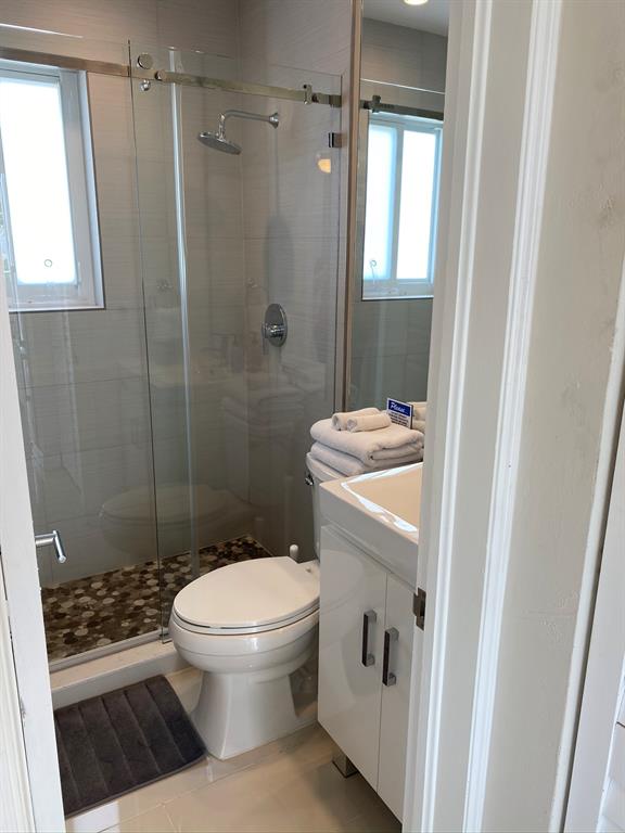 1705 North Riverside Drive, Unit 8 Pompano Beach, FL 33062 - Photo 22 of 40 a bathroom with a granite countertop toilet a sink a shower and a window