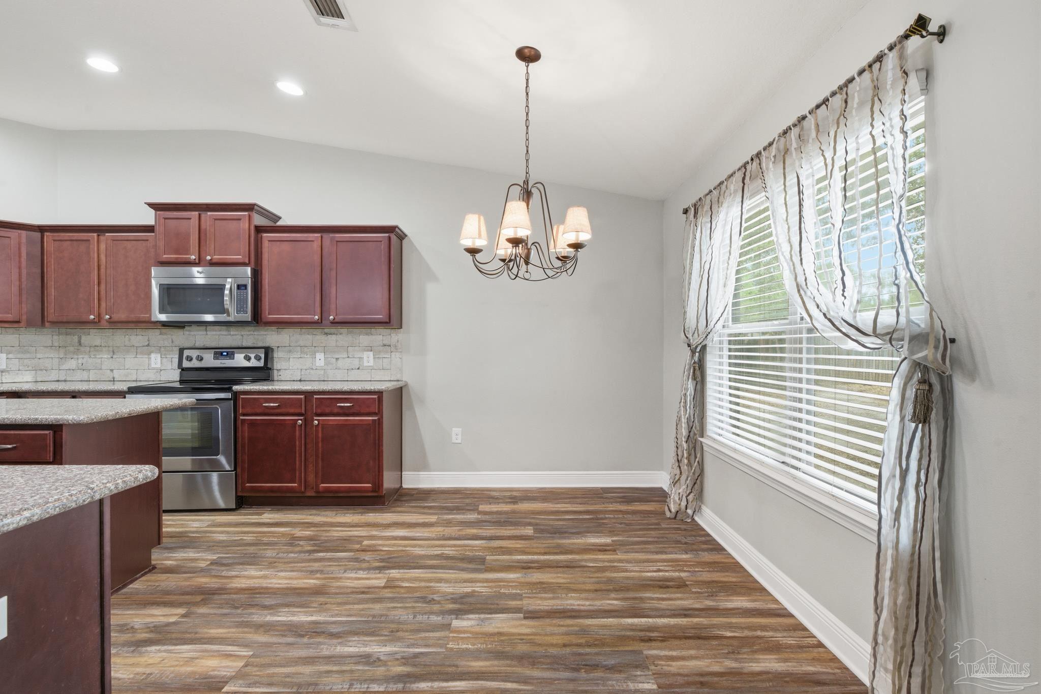 5661 Cane Syrup Circle Pace, FL 32571 - Photo 8 of 20 a kitchen with stainless steel appliances granite countertop a stove a sink and a wooden floors