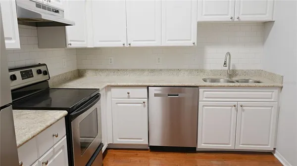 a kitchen with granite countertop white cabinets and a white stove