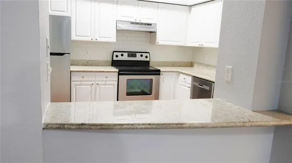 a kitchen with granite countertop white cabinets and white appliances