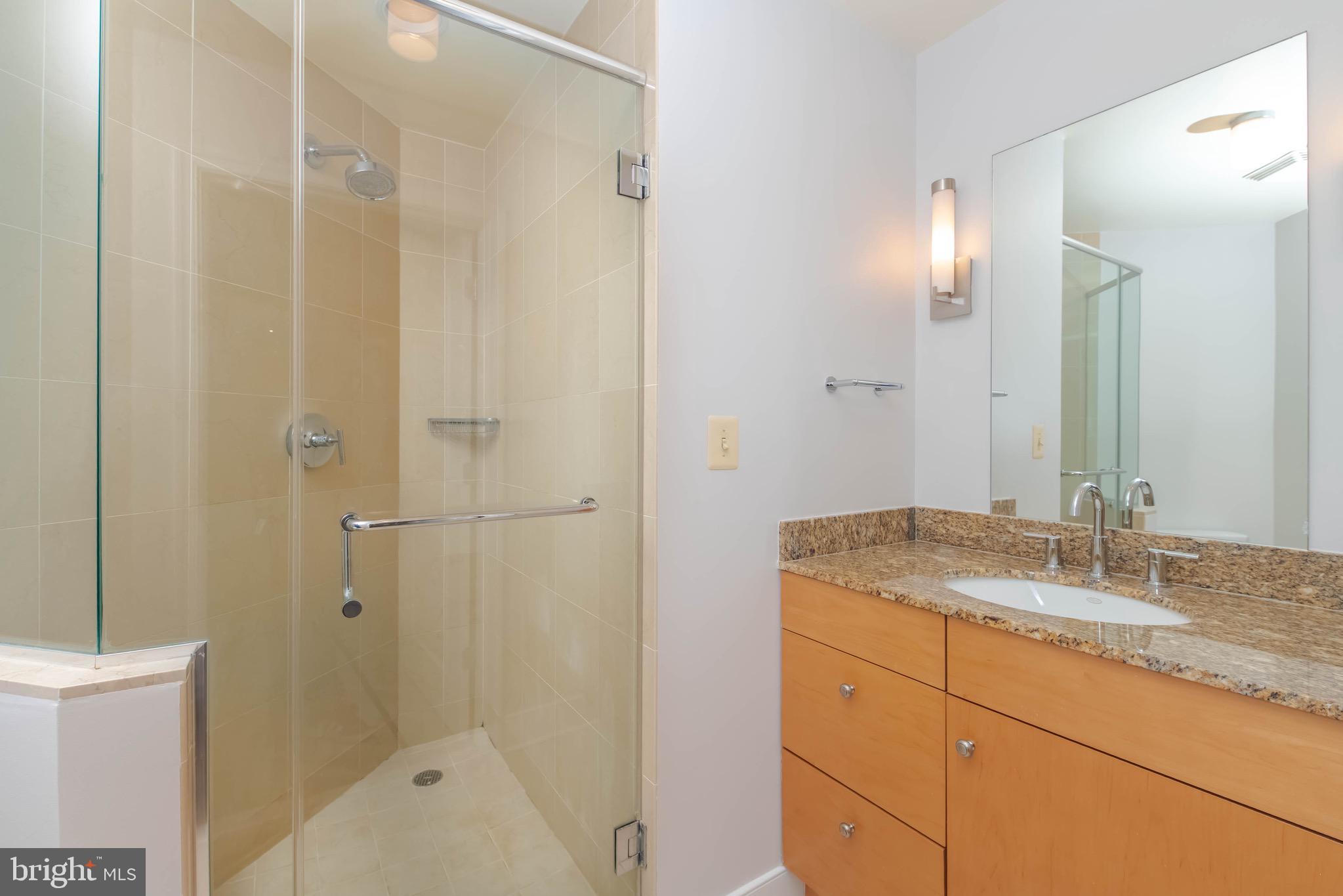 675 President Street, Unit 2207 Baltimore, MD 21202 - Photo 16 of 30 a bathroom with a granite countertop sink a mirror a bathtub and shower
