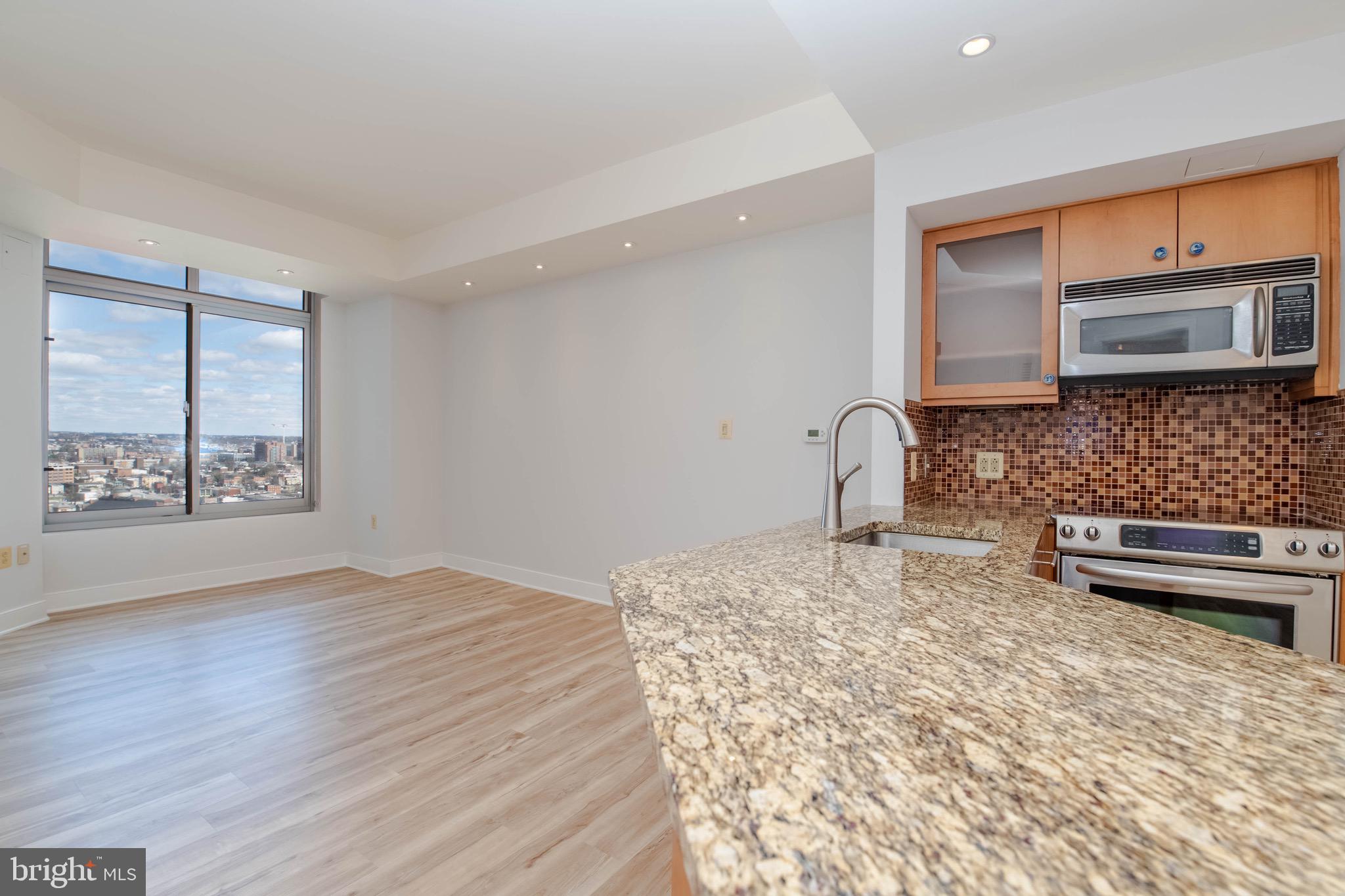 675 President Street, Unit 2207 Baltimore, MD 21202 - Photo 5 of 30 a kitchen with granite countertop a stove a sink and a microwave