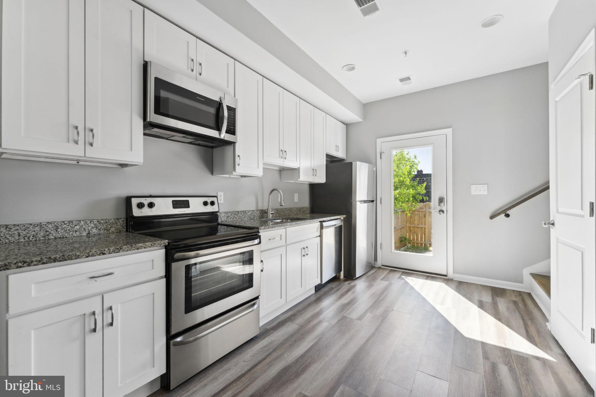 a kitchen with stainless steel appliances granite countertop a stove a sink and a microwave