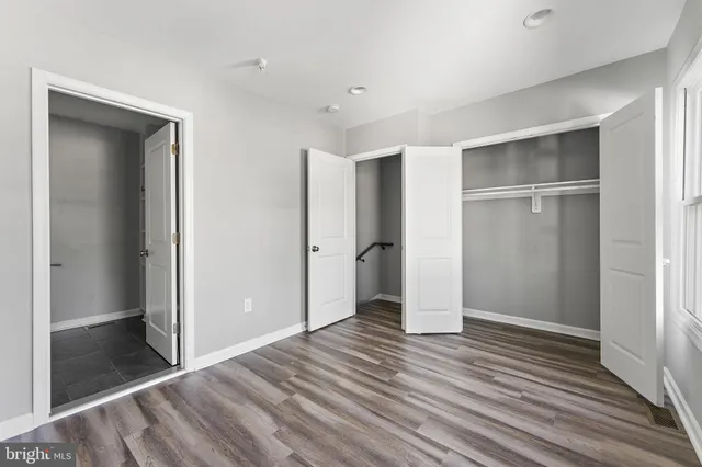 a view of an empty room with wooden floor and closet