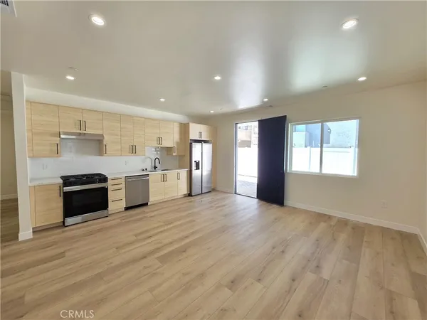 a large kitchen with stainless steel appliances granite countertop a stove a sink and a refrigerator