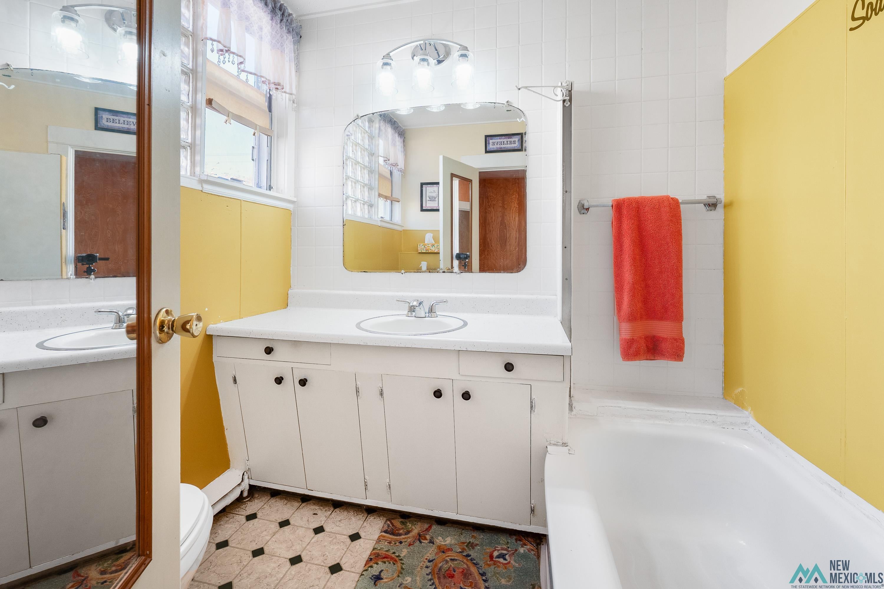 727 South 6th Street Raton, NM 87740 - Photo 25 of 47 Full bathroom with two vanities, a tub, and tile walls