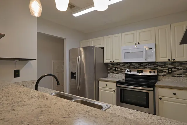 a kitchen with granite countertop white cabinets and appliances