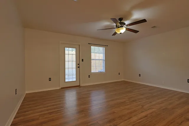 a view of empty room with wooden floor and fan