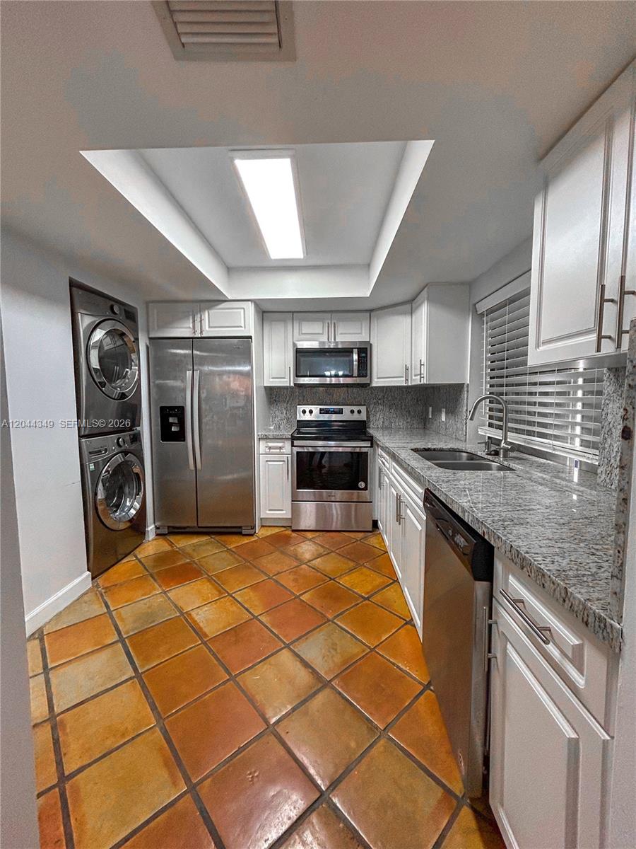 14970 Southwest 48th Terrace, Unit 27G Miami, FL 33185 - Photo 3 of 14 a large kitchen with stainless steel appliances granite countertop a refrigerator and stove