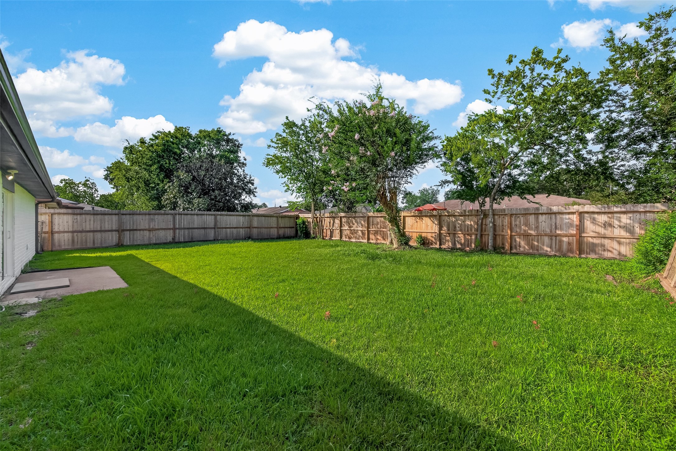 16619 Tibet Road Friendswood, TX 77546 - Photo 28 of 29 Spacious backyard with well-maintained grass, bordered by a wooden fence, and featuring mature trees. Ideal for outdoor activities and relaxation.