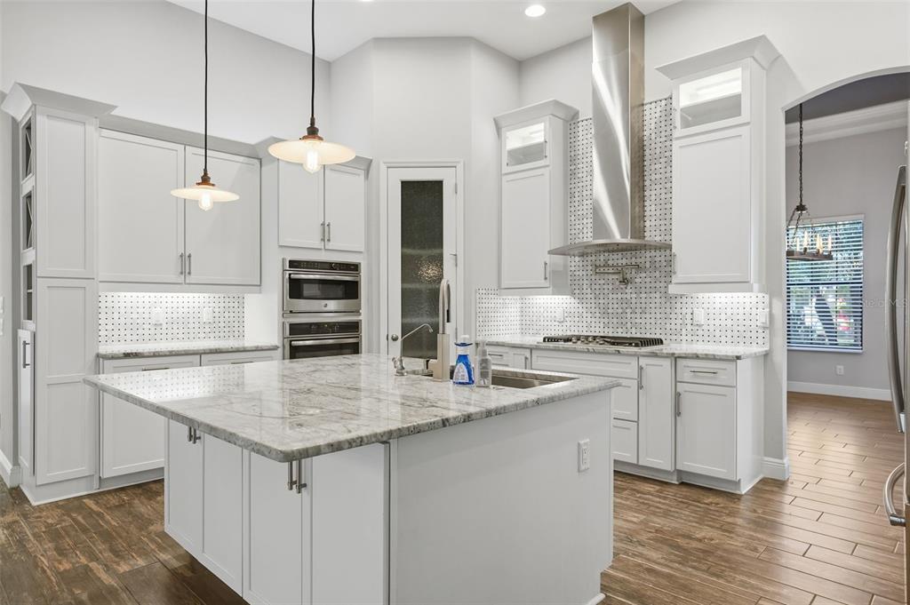 31999 Watoga Loop Wesley Chapel, FL 33543 - Photo 11 of 67 a kitchen with stainless steel appliances granite countertop a sink dishwasher a stove and a refrigerator with wooden floor