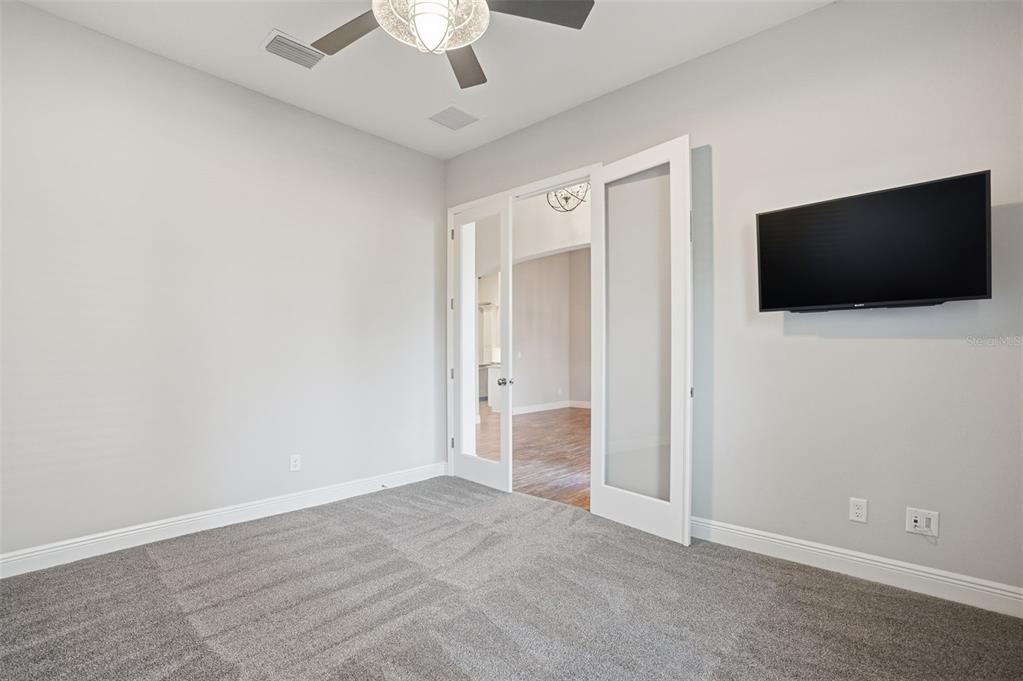 31999 Watoga Loop Wesley Chapel, FL 33543 - Photo 24 of 67 an empty room with a flat screen tv and a ceiling fan