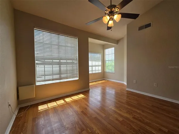 a view of an empty room with window and wooden floor