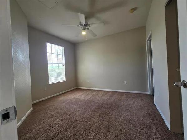 an empty room with windows and chandelier fan