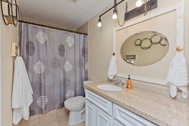 a bathroom with a granite countertop sink toilet and a mirror