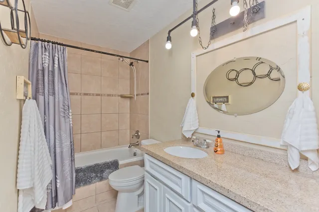 a bathroom with a granite countertop sink a toilet and a shower