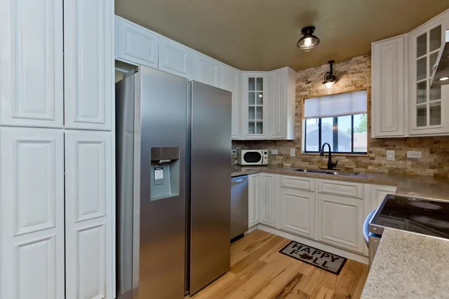 a kitchen with stainless steel appliances granite countertop a refrigerator and a sink
