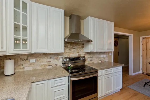 a kitchen with stainless steel appliances granite countertop white cabinets and a stove