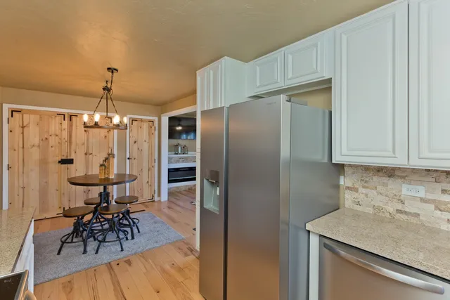 a kitchen with stainless steel appliances granite countertop a table chairs stove and refrigerator