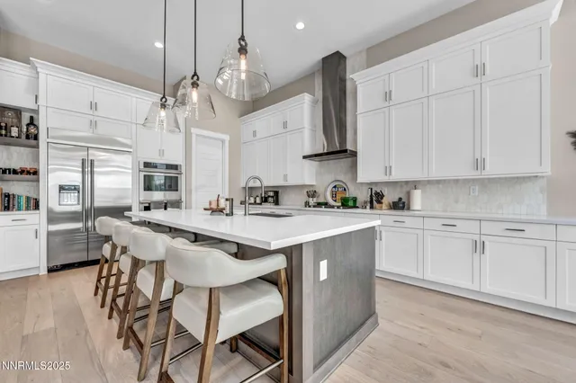 a kitchen with stainless steel appliances kitchen island granite countertop a wooden floor and white cabinets