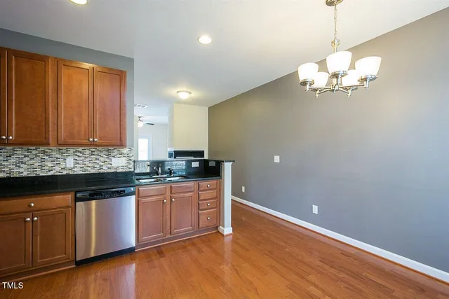 a kitchen with stainless steel appliances granite countertop a sink a microwave oven a refrigerator with wooden floor and cabinets