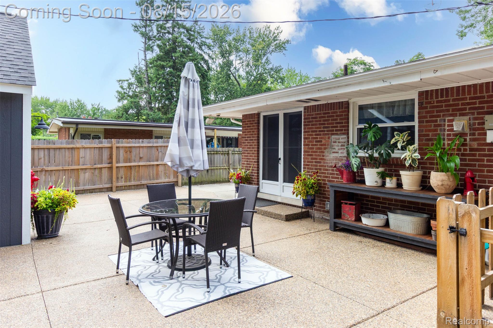 29604 Chelmsford Road Southfield, MI 48076 - Photo 38 of 39 Expansive concrete patio with a privacy fence, brick exterior, and a built-in outdoor shelving unit