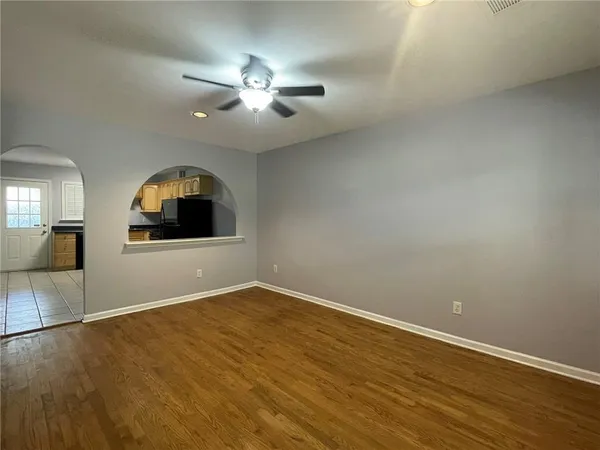 an empty room with wooden floor mirror and windows