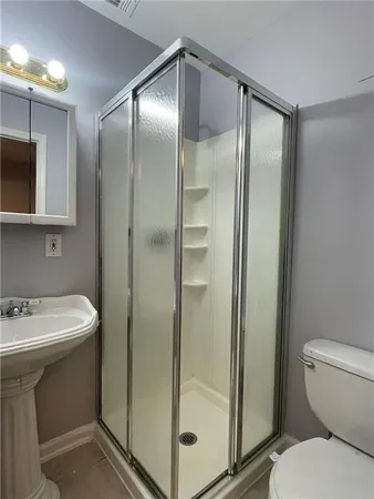 a bathroom with a shower sink mirror and toilet