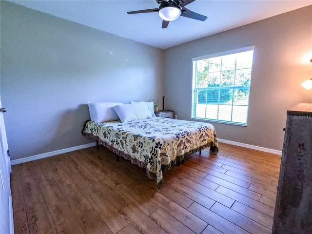 a bedroom with a bed lamp and wooden floor