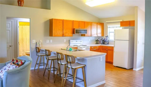 a kitchen with stainless steel appliances granite countertop a refrigerator a sink a stove and a dining table with wooden floor