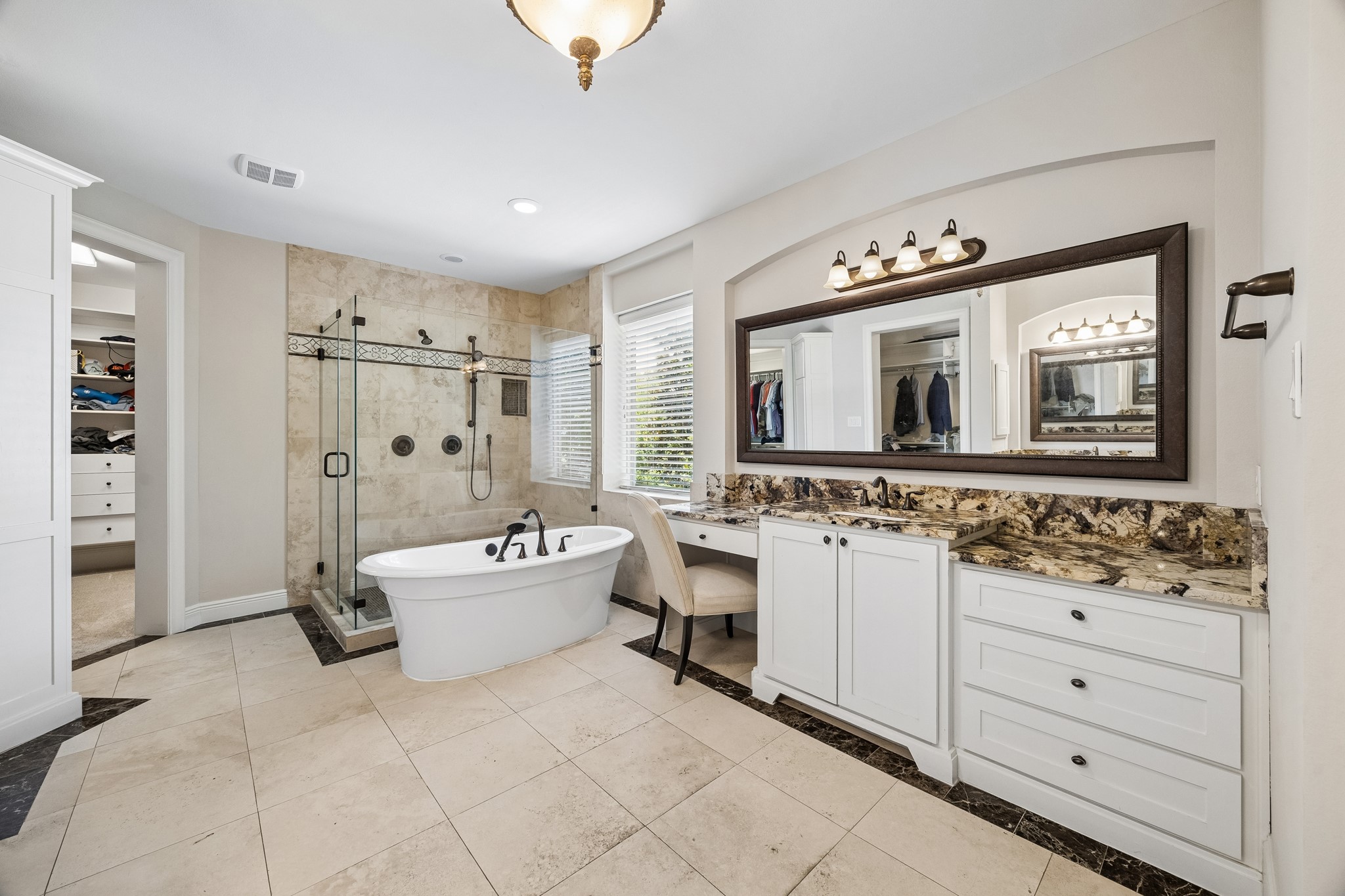 1360 Chippendale Road Houston, TX 77018 - Photo 18 of 34 Spa-inspired primary bath designed for both luxury and functionality featuring a freestanding soaking tub, dual oversized walk-in closets with built-ins, dedicated vanity space, and extensive granite-topped cabinetry. Thoughtfully designed layout offers abundant storage while creating a serene retreat connected to the primary suite.
