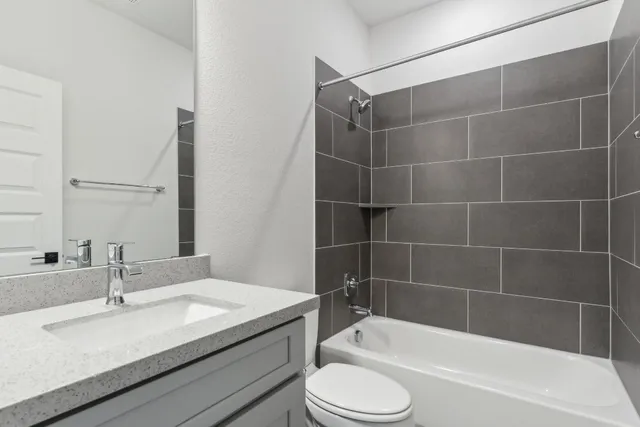 a bathroom with a granite countertop sink a toilet and bathtub