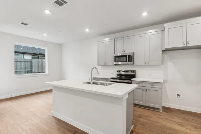 a kitchen with granite countertop white cabinets and black stainless steel appliances