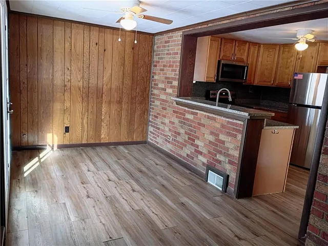 a kitchen with stainless steel appliances granite countertop a refrigerator a stove and a sink with wooden floor