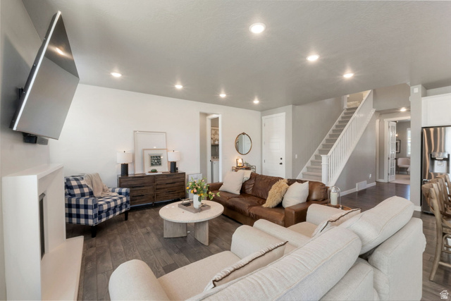 2319 North 3370 West Lehi, UT 84048 - Photo 3 of 30 Spacious living area featuring wood-finish flooring, recessed lighting, a white staircase with carpeted treads, and a built-in electric fireplace