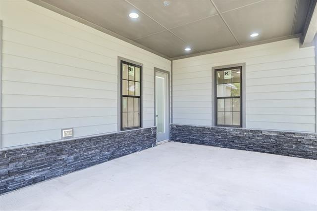 2936 Henry Road Lancaster, TX 75134 - Photo 28 of 28 Covered patio featuring plank siding and a stacked stone accent wall
