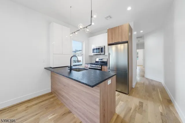 a kitchen with stainless steel appliances granite countertop a sink a refrigerator and a stove