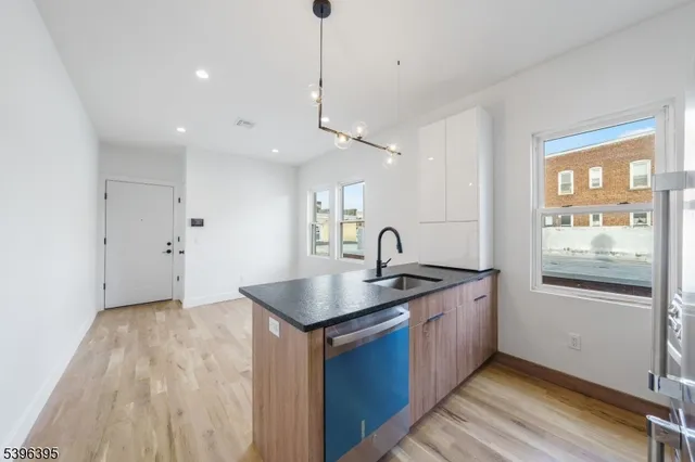 a kitchen with stainless steel appliances granite countertop a sink a stove and a wooden floor