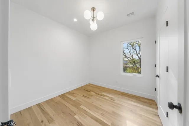 a view of empty room with wooden floor and ceiling fan