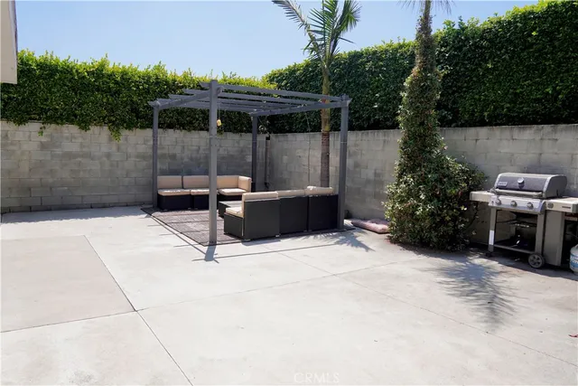 a backyard of a house with table and chairs potted plants and large tree