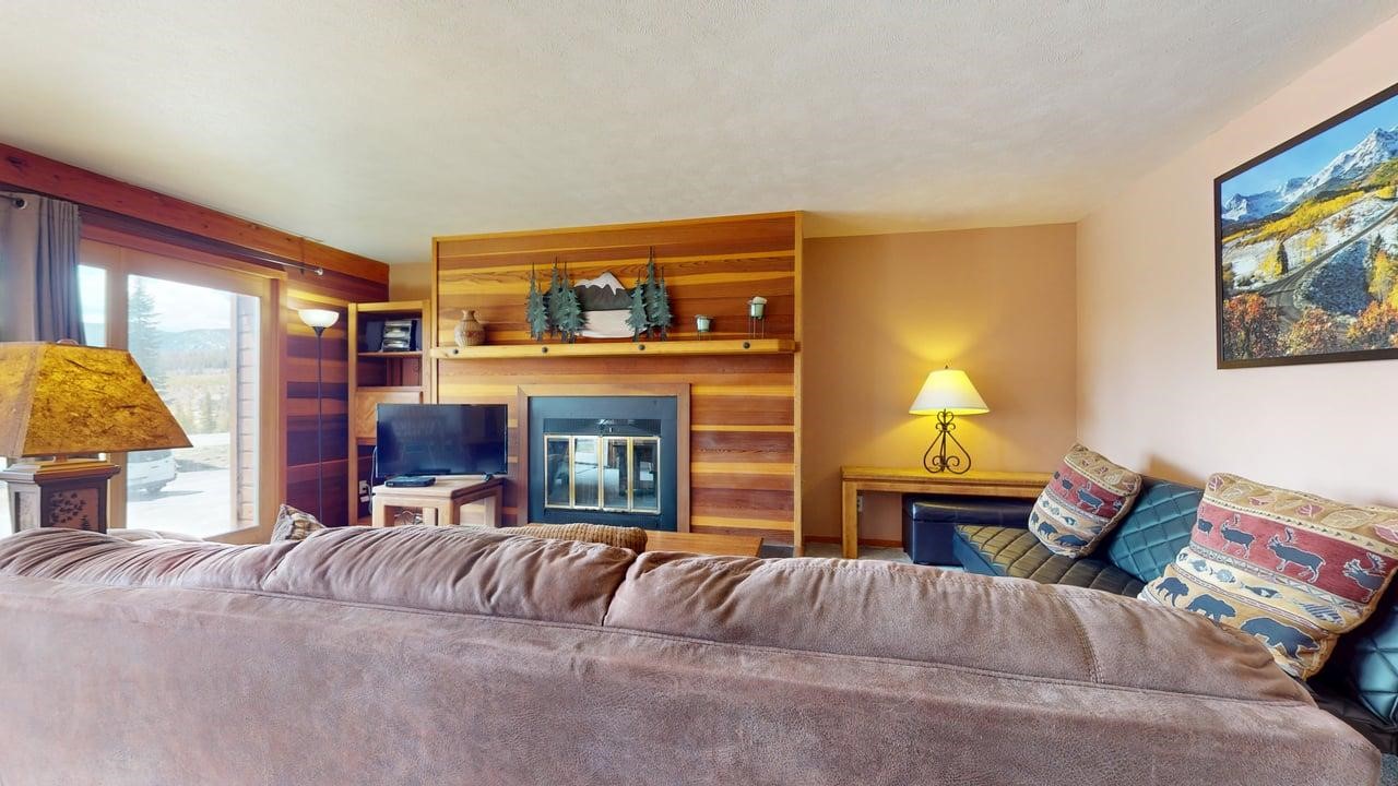 91200 Ryan Gulch Road, Unit 213 Silverthorne, CO 80498 - Photo 28 of 33 a living room with furniture a fireplace and a flat screen tv