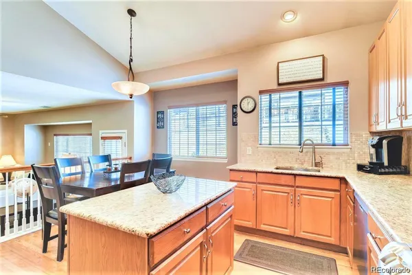 a kitchen with stainless steel appliances granite countertop a stove a sink a dining table and chairs with wooden floor